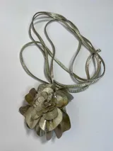 Accesorio dorado con forma de flor que puede usarse como colgante, faja o gargantilla.