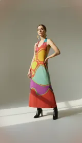 Vestido midi con estampado abstracto en tonos naranja, amarillo, verde y violeta. Tiene escote halter regulable y silueta fluida.