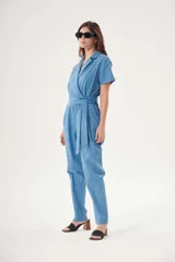 Mono celeste de corte cruzado con cuello camisero, mangas cortas, bolsillos laterales y cinturón de lazo.