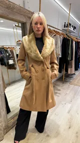 Tapado color camel con cuello de piel sintética color beige, doble botonadura y lazo para ajustar en la cintura.