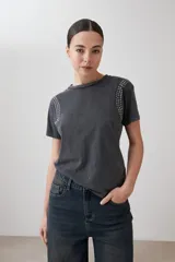 Remera rosa pastel de manga corta con tachas plateadas en los hombros.