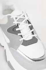 Zapatillas blancas con recortes en diferentes tonos de gris, cordones y plataforma irregular de 5cm.