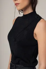 Musculosa negra con cuello alto y detalle de botones decorativos en el lateral.