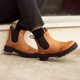 Bota de cuero color terracota, de caña media con elástico lateral y suela de neolite negra.