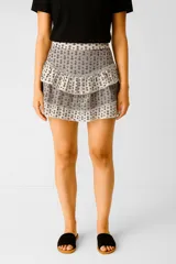 Falda mini de algodón color crudo con estampado de flores pequeñas en negro. Tiene dos volados superpuestos y cintura elastizada.