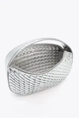 Bolso de mano plateado con efecto trenzado y asa corta. Incluye correa extraíble para usar como bandolera. Cierre con cremallera metálica.