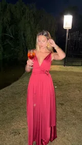 Vestido largo color bordó con escote en V profundo y tirantes anchos. Presenta un fruncido drapeado en la cintura con un detalle de hebilla metálica. La falda es larga y fluida.