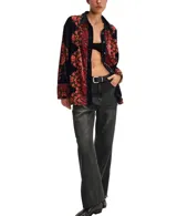 Camisa de terciopelo negro con estampado floral en tonos rojos y naranjas. Tiene cuello clásico, cierre frontal con botones y mangas largas con puños.