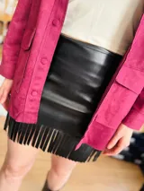 Minifalda negra de cuero sintético con flecos en el ruedo.