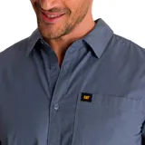 Camisa de popelina verde con cuello abotonado, cierre frontal con botones, bolsillo de parche en el pecho izquierdo, mangas largas con trabillas para enrollar y dobladillo camisero.