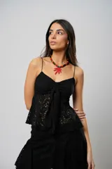 Top de encaje negro con breteles finos y lazo en el centro del busto.