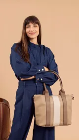 Cartera de mano color beige con divisiones y detalles en marrón y blanco. Tiene correa corta, correa larga ajustable, bolsillo trasero y bolsillos internos.