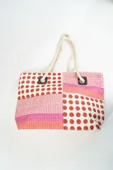 Bolso tipo tote con diseño de bloques de color rosa, rojo y blanco con estampado de lunares y textura tejida. Asas de soga gruesa.
