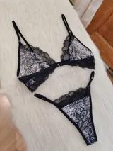 Conjunto de lencería compuesto por un corpiño triangular sin aro con estampado animal print y detalles de encaje negro, y una bombacha tipo colaless con el mismo estampado y borde de encaje negro. El corpiño tiene cierre frontal.