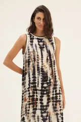 Vestido largo de corte recto con estampado tie-dye en tonos beige, marrón y negro. Tiene cuello redondo y sisas con ribete negro.