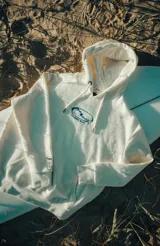 Hoodie blanco con capucha y cordones ajustables, con logo estampado en el pecho.