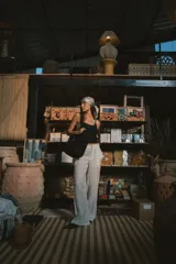 Pantalón de vestir negro de tiro alto, corte recto y pierna ancha. Presenta pliegues frontales y bolsillos laterales.