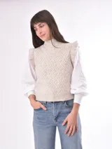 Chaleco tejido color beige con cuello alto y volados en los hombros. Diseño con patrón de rombos en relieve.
