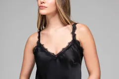 Vestido largo negro de seda con breteles finos y escote en V. Presenta un panel de encaje floral en la parte inferior, con corte asimétrico.