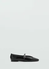 Zapato tipo ballerina color negro charol, con punta redonda, cierre de hebilla y detalle de hebilla con strass.