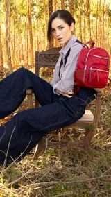 Mochila roja de tafeta con doble apertura superior con cierre y tiradores metálicos. Incluye bolsillos internos, tres bolsillos con cierre metálico al frente y uno posterior. Tiene asa corta de mano y correas para la espalda regulables.