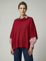 Poncho tejido de acrílico color rojo intenso, con cuello vuelto suave y corte asimétrico.