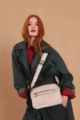 Bandolera color rosa viejo con detalles en cuero marrón claro, múltiples cremalleras metálicas y herrajes plateados. Incluye correa ancha ajustable con el logo de la marca.