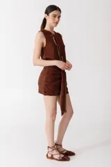 Top sin mangas color ladrillo, tejido en punto arroz con textura suave. Presenta un corte recto y lazos finitos decorativos en el frente, simulando una abertura.