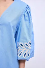 Vestido blanco de lino con escote en V, mangas cortas abullonadas y bordados florales en beige en mangas y ruedo.