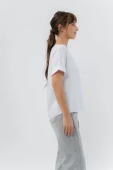 Remera blanca de viscosa liviana, con escote redondo y mangas cortas con vuelta.