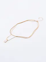 Collar dorado de doble cadena con dije rectangular blanco.