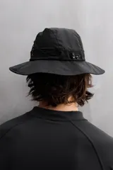 Sombrero tipo bucket color beige, confeccionado en tejido técnico con perforaciones en la copa para mejorar la transpirabilidad. Tiene ajuste elástico y ala ancha con pespuntes.