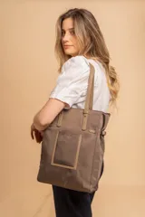 Cartera tipo tote bag color negro, con doble asa de mano y correa bandolera ajustable. Presenta un bolsillo rectangular en el frente.