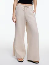 Pantalón de lino negro con elástico en la cintura, tiro medio y calce relajado. Lleva tiras en color gris aplicadas a los laterales, que quedan sueltas en la parte inferior y pueden anudarse.