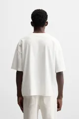 Camiseta blanca de corte relaxed fit, cuello redondo y manga corta. Estampado combinado a contraste en el delantero con imagen borrosa de flor y texto en azul.
