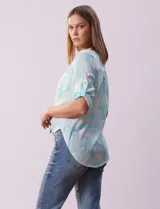 Blusa de gasa estampada azul con diseño paisley, marca Ruby Rd. Cuello a la base, escote en v y abertura con botones. Delantera con bolsillos. Largo de manga regulable con presilla y botón. Terminación de ruedo con nudo.