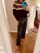 Sweater negro con diseño geométrico en blanco, rosa y amarillo en la parte superior.