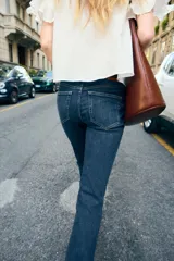 Pantalón de jean azul oscuro, de tiro bajo, corte slim fit y bootcut. Con cinco bolsillos y cierre frontal con cremallera y botón.