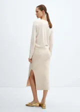 Sweater de punto fino color crudo, con escote en V y mangas largas.