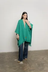 Ruana verde esmeralda de tejido de punto con flecos en el borde inferior.