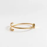 Pulsera dorada flexible con dije en forma de corazón y borlas doradas, fabricada en acero con acabado en oro de 18k.
