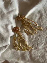 Aros colgantes dorados con forma de ramitas irregulares. Hechos a mano en bronce y porcelana con mix de piedras y materiales para darle textura.
