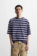 Camiseta de hombre a rayas horizontales azul marino, blancas y rojas, de corte relaxed fit, cuello redondo y manga corta.