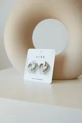 Aros de acero quirúrgico hipoalergénico con forma de argolla plateada y dije circular colgante de piedra natural color azul.