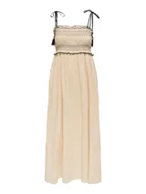 Vestido midi color crema, con tirantes finos ajustables, escote recto y cuerpo fruncido con detalle de borlas negras.