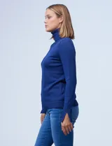 Polera de punto fino marca Nienty, color blanco, con cuello alto volcado y mangas largas con detalle de tajo en los puños.