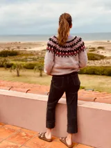 Sweater gris con diseño geométrico en negro y rojo alrededor del cuello, de lana tejido a mano con estilo nórdico.