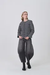 Chaqueta de manga larga con cuello a la base y cierre frontal. Presenta un estampado geométrico repetitivo en blanco y negro.