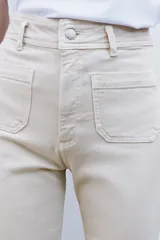 Pantalón de jean de tiro alto color negro con pierna ancha, bolsillos delanteros y traseros, y cierre frontal con cremallera y botón metálico.