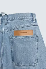 Pantalón de jean celeste de corte holgado y amplio en toda la pierna, tiro medio, tejido rígido, cinco bolsillos, efecto lavado, parche en trasero y bolsillo de vivo en pernera.